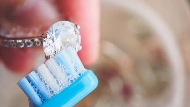 a person polishes a diamond ring with a brush