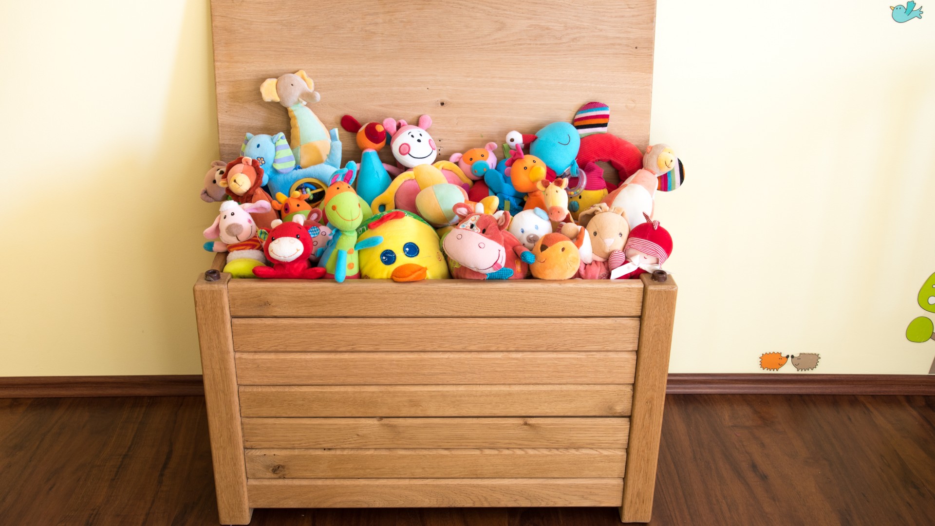 a toy box full of soft toys in a child's bedroom